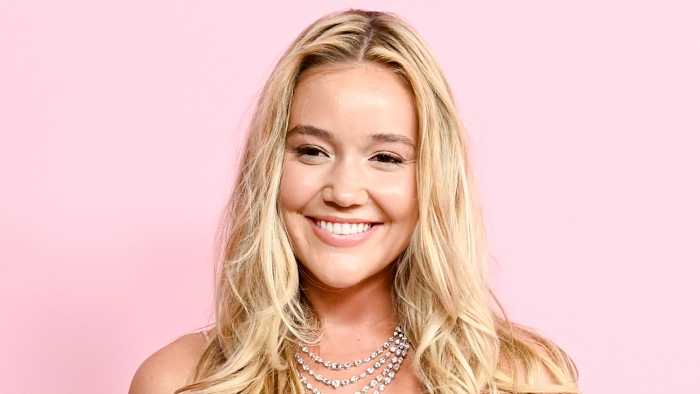 Olivia Ponton poses in a diamond necklace in front of a pink backdrop.